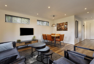 Soggiorno e sala da pranzo moderni nella lodge Module Wood a Bospark Ede, Paesi Bassi, con arredi eleganti.