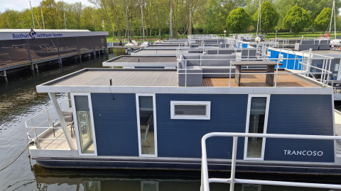 Péniche nommée Havenlodge à Marina Parcs Naarden aux Pays-Bas, amarrée dans une marina entourée d’arbres.