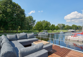 Loungebank op het dek van een havenlodge in Marina Parcs Naarden, Nederland, met uitzicht op boten.