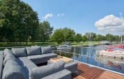 Modern outdoor seating on a houseboat at Marina Parcs Naarden, Netherlands, overlooking docked boats.