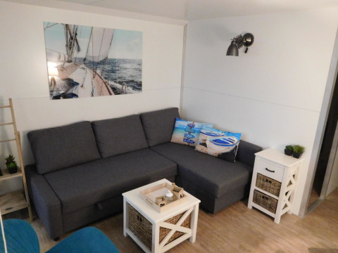 Sala de estar luminosa y moderna en una casa flotante en Marina Parcs Naarden, con sofá gris y decoración náutica.