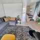Modern living room on houseboat 'De Hoop' at Marina Parcs, with gray sofa, rug, table and kitchenette.