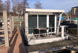 Moderne husbåd ved kajen i Marina Parcs - Jachthaven De Hoop, Nederlandene, med udendørs siddeplads.