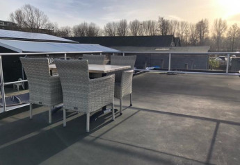 Rooftop terrace of houseboat De Hoop at Marina Parcs, Netherlands, with wicker dining set and morning sun.