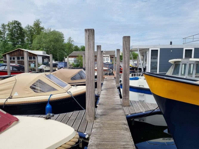 Pasarela de madera entre barcos atracados en Marina Parcs, con vistas a la casa flotante de los Países Bajos.