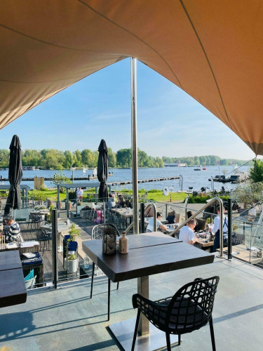 Blick von einem Hausboot-Café bei Marina Parcs - Jachthaven De Hoop, mit Terrasse am Wasser in den Niederlanden.