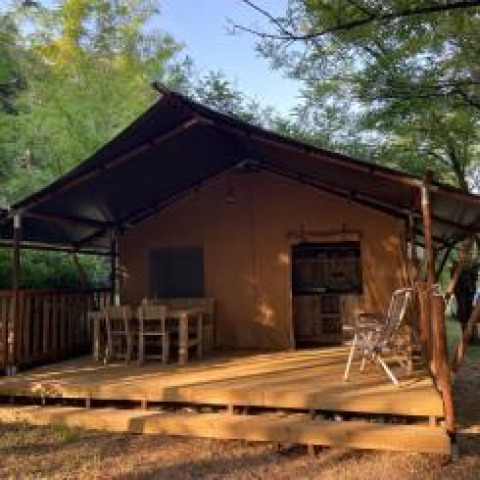Tienda safari con instalaciones sanitarias en Camping Monti del Sole, Italia, rodeada de vegetación.