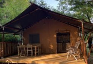Tienda safari con instalaciones sanitarias en Camping Monti del Sole, Italia, rodeada de vegetación.