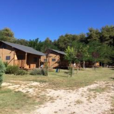 Tiendas safari con instalaciones sanitarias en Camping Monti del Sole, Italia, rodeadas de árboles y naturaleza.
