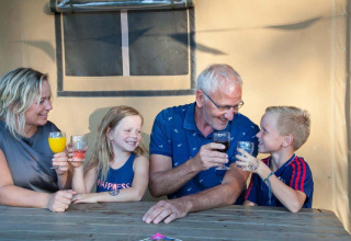 Famiglia che si gode una bevanda insieme davanti a una tenda safari al Recreation Park Den Blanken, Paesi Bassi.