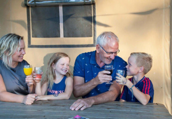 Famiglia che si gode una bevanda insieme davanti a una tenda safari al Recreation Park Den Blanken, Paesi Bassi.