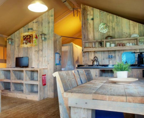 Vista interna di una tenda safari al Recreation Park Den Blanken, con mobili rustici in legno e cucina.
