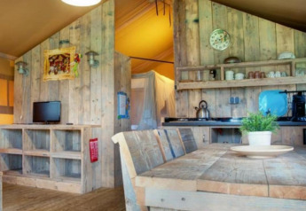 Vista interna di una tenda safari al Recreation Park Den Blanken, con mobili rustici in legno e cucina.
