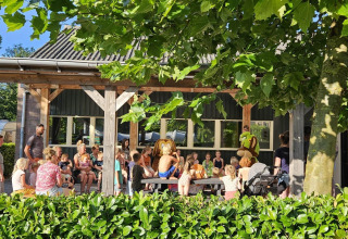 Children and adults gather outside a safari tent at Recreation Park Den Blanken in the Netherlands on a sunny day.