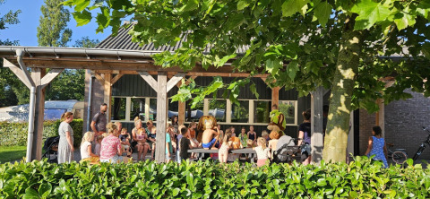 Children and adults gather outside a safari tent at Recreation Park Den Blanken in the Netherlands on a sunny day.
