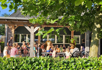 Children and adults gather outside a safari tent at Recreation Park Den Blanken in the Netherlands on a sunny day.