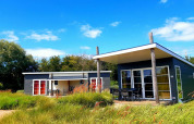 Dos casas diminutas modernas en Comfort Lodge, Kompas Camping Westende, Bélgica, rodeadas de naturaleza verde.