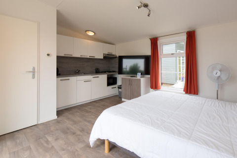 Interiør af Comfort Lodge tiny house på Kompas Camping Westende i Belgien med seng, køkken og tv.