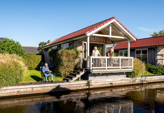 Meine Luxe lodge bij Tusken de Marren in Nederland, mensen ontspannen op de veranda en aan het water.