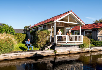 Meine Luxe lodge bij Tusken de Marren in Nederland, mensen ontspannen op de veranda en aan het water.
