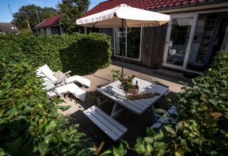 Udendørs terrasse ved Meine Luxe lodge med hvidt havemøblement og parasol i Tusken de Marren, Holland.