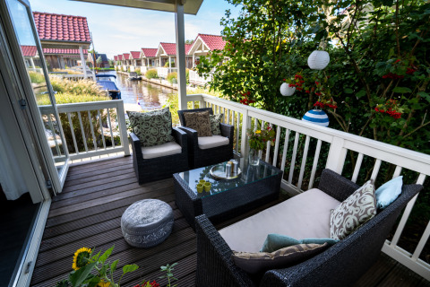 Afslappet terrasse på Meine Luxe-lodgen ved vandet i Tusken de Marren, Nederlandene, med udendørsmøbler.