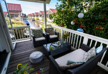 Afslappet terrasse på Meine Luxe-lodgen ved vandet i Tusken de Marren, Nederlandene, med udendørsmøbler.