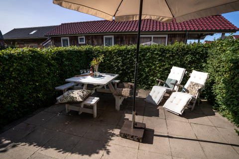 Udendørs terrasse med parasol, spisebord og liggestole på Meine Luxe ved Tusken de Marren, Holland.