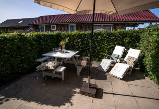 Terraza exterior con sombrilla, mesa de picnic y tumbonas en Meine Luxe, Tusken de Marren, Países Bajos.
