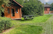 Foto de una cabaña de troncos básica en Urban-Gardens Ieper, Bélgica, junto a césped y mesa de picnic.