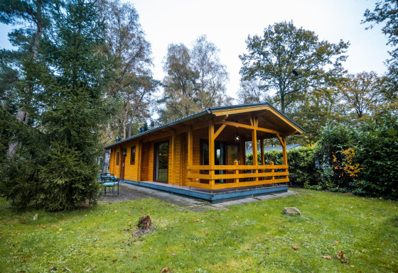 Houten Wellness Lodge bij Buitencentrum Hessenheem in Nederland, omgeven door bomen en grasveld.