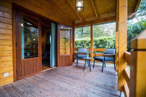 Acogedora terraza de madera en la wellness lodge de Buitencentrum Hessenheem, Países Bajos, con asientos.