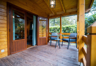 Acogedora terraza de madera en la wellness lodge de Buitencentrum Hessenheem, Países Bajos, con asientos.
