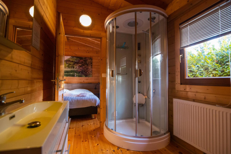 Modernes Badezimmer mit Holzwänden, runder Dusche und Fenster in der Wellness Lodge in Hessenheem.