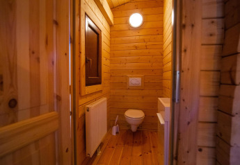 Baño con paredes de madera y sanitario suspendido en la Wellness Lodge de Buitencentrum Hessenheem, Países Bajos.