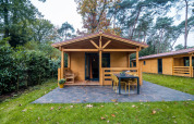 Wellness lodge bij Buitencentrum Hessenheem, Nederland, houten chalet met terras in bosrijke omgeving.