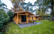Lodge bien-être en bois au Buitencentrum Hessenheem, Pays-Bas, entouré d’arbres et de verdure.