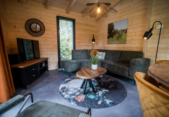 Stue i wellness lodge ved Buitencentrum Hessenheem, Holland, med sofa, tv og moderne indretning.