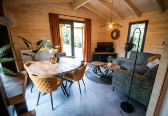 Gemütliche Wellness-Lodge in Buitencentrum Hessenheem mit Holzwänden, Sofa, Tisch und viel Tageslicht.