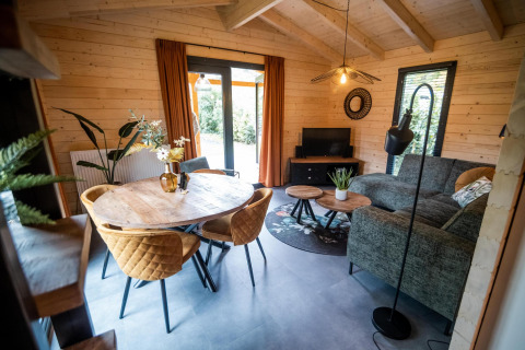 Area living della Wellness Lodge al Buitencentrum Hessenheem con interni in legno e arredamento moderno.
