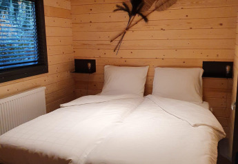 Et hyggeligt soveværelse i wellness lodge på Buitencentrum Hessenheem, Nederlandene, med trævægge og to senge.