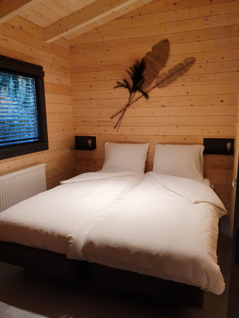 Chambre douillette dans une wellness lodge au Buitencentrum Hessenheem, Pays-Bas, avec lits jumeaux et murs en bois.