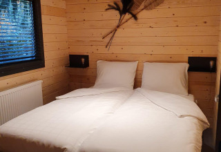 Chambre douillette dans une wellness lodge au Buitencentrum Hessenheem, Pays-Bas, avec lits jumeaux et murs en bois.