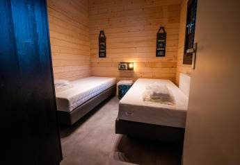 Twee enkele bedden in een warme houten kamer van de Wellness Lodge bij Buitencentrum Hessenheem, Nederland.