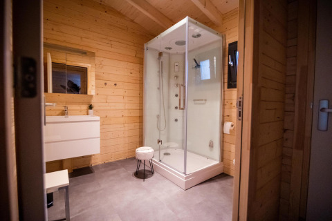 Salle de bain moderne en lodge bien-être avec murs en bois, douche et lavabo à Buitencentrum Hessenheem, Pays-Bas.