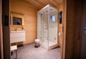 Salle de bain moderne en lodge bien-être avec murs en bois, douche et lavabo à Buitencentrum Hessenheem, Pays-Bas.