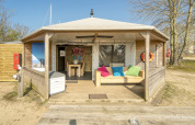 Lodge Dune House a Marina Parcs Almere nei Paesi Bassi con veranda in legno e cuscini colorati.