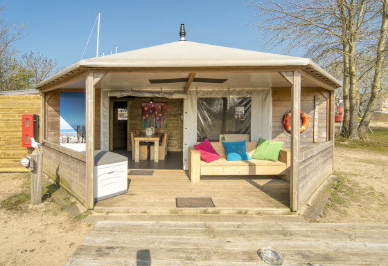 Udsigt til Dune House-lodge ved Marina Parcs Almere, Nederlandene, med farverige puder og træmøbler.