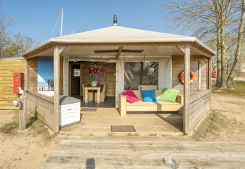 Lodge Dune House a Marina Parcs Almere nei Paesi Bassi con veranda in legno e cuscini colorati.