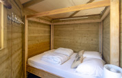 Dormitorio de madera con cama con dosel en Dune house de Marina Parcs Almere, Países Bajos, ambiente acogedor.
